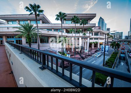 Tampa. FL – 12. September 2021; der Verkehr am frühen Morgen unterquert eine Fußgängerbrücke in der Innenstadt, die mit dem Tampa Convention Center und der Skyline im Hintergrund verbunden ist Stockfoto