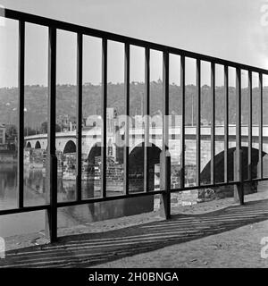 Die Trierer Alte Moselbrücke, durch ein Gitter am Ufer der Mosel gesehen, Deutschland 1930er Jahre. Die alte Brücke über die Mosel in Trier, durch ein Geländer am Ufer gesehen, Deutschland 1930. Stockfoto