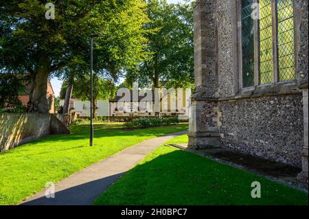 Blick auf die St. Nicholkirche und den Kirchhof zur Church Street mit dem White Swan Pub und dem Heilsarmee-Haus in North Walsham, Norfolk, England. Stockfoto