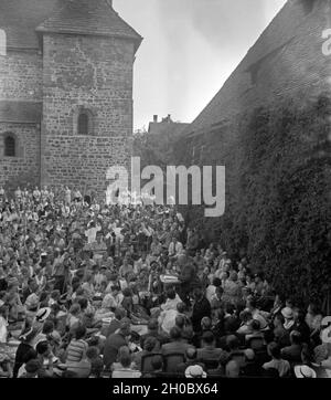 Ein n. (am Schreibtisch) wird beim Dichtertreffen im Klosterhof von lippoldsberg an der Weser von Zuhörern umlagert, 1930er Jahre. Ein deutscher Autor (Schreibtisch) wird durch das Publikum an der Dichter treffen in Lippoldsberg, Hessen, 1930er Jahre umgeben. Stockfoto