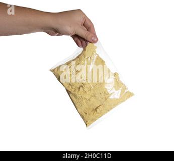 Senfpulver in einem Beutel in der Hand eines Mannes auf weißem Hintergrund, isolieren. Nahaufnahme Stockfoto