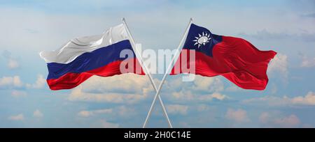 Flaggen von Russland und Taiwan winken im Wind auf Fahnenmasten gegen den Himmel mit Wolken am sonnigen Tag. Symbolisieren Beziehung, Dialog zwischen zwei Ländern Stockfoto