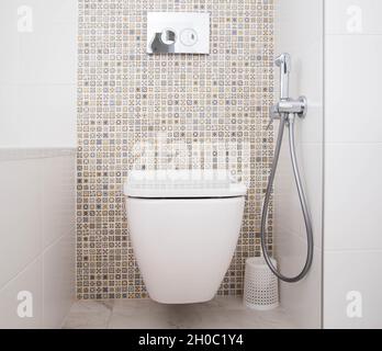 Moderne Wand-WC mit Dusche für private Räume. Weißes und sauberes Badezimmer, Hintergrund Stockfoto