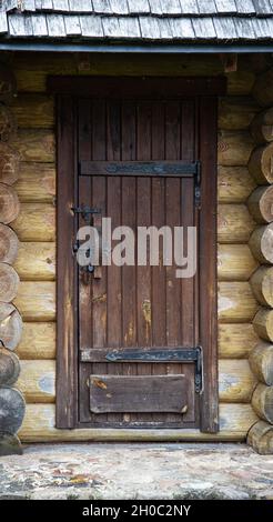 Braune Holztür in einer Blockhütte mit schmiedeeisernen Scharnieren und einem Schloss, antik Stockfoto