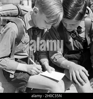 Zwei Hitlerjungen schreiben eine aufnäher von einer Wanderung, Deutschland 1930er Jahre. Zwei Hitler Jugend schreiben Sie eine Postkarte aus eine wandernde Reise, Deutschland 1930. Stockfoto