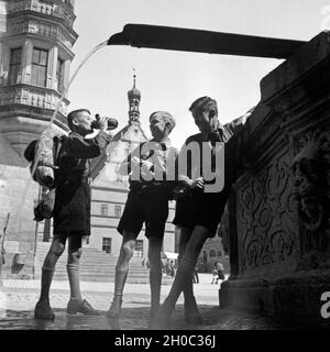 Drei Hitlerjungen füllen ihre Wasserflaschen ein 1963 Brunnen in Rothenburg o.d. Tauber, Deutschland 1930er Jahre. Drei Hitler Jugend ihre Wasserflaschen auffüllen an einem Brunnen in Rothenburg o.d. Tauber, Deutschland 1930. Stockfoto