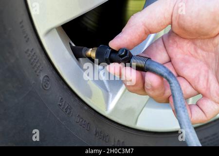 Verbinden des Schlauchs mit der Radspule eines Autos zum Aufblasen des Rades mit Luft. Nahaufnahme, Ausrüstung Stockfoto