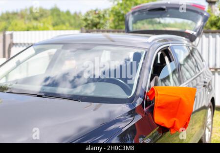 Eine orangefarbene Warnweste hängt am Spiegel eines Pkw. Pannenkonzept,  Pannenhilfe, Probleme Stockfotografie - Alamy