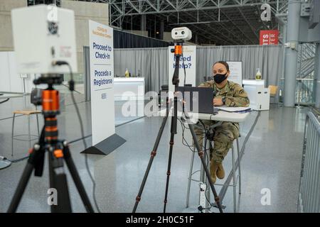 US Army Sgt. Yira Caceres, eine Installateurin und Betreuerin für Kabelsysteme, die der Signal Co. 42nd Infantry Division zugewiesen ist, überwacht die Temperaturkontrollen der Einwohner von New York mithilfe einer ausgeklügelten Software, um die staatlichen Bemühungen zur Bereitstellung von Massen-COVID-19-Impfungen zu unterstützen, die vom New Yorker State Department of Health im Javits Convention Center in Manhattan durchgeführt werden, New York, 21. Januar 2021. Die Nationalgarde hat mehr als 350 Wachmänner und Frauen, die zur Unterstützung des Personals an der Impfstelle eingesetzt werden. Das Gesundheitsministerium des Bundesstaates New York unternimmt Impfmaßnahmen für lebenswichtige Wor Stockfoto