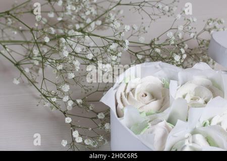 Hausgemachter Marschmalg in einer Geschenkbox. Zethyr Rosen. Herzförmige Schachtel. Gebunden mit einem Band, das an eine Schleife gebunden ist. Marshallrosen. Herzförmige Schachtel. In der Nähe von i Stockfoto