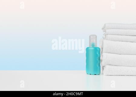 Stapel Handtücher, Flaschen mit Shampoo auf weißem Tisch Stockfoto