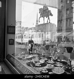 Das Denkmal von Kaiser Wilhelm I. spiegelt sich im-Schaufenster des Haushaltwarengeschäfts auf dem Burgplatz in Essen, Deutschland 30er Jahre. Skulptur von Kaiser Wilhelm I. wird im Fenster eines Kaufhauses am Burgplatz in Essen, Deutschland der 1930er Jahre wider. Stockfoto