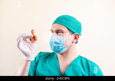 Ein Arzt in einer Maske und Handschuhen, mit einem Spinner in den Händen. Stockfoto