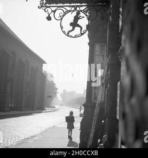 Schulkind vor einem Haus mit dem Rattenfänger in Hameln an der Weser, Deutschland 1930er Jahre. Schule Mädchen vor einem Haus mit Symbol der Rattenfänger in der Altstadt von Hameln auf der Weser, Deutschland 1930. Stockfoto