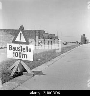 Warnhinweis auf eine Baustelle in 100 Metern bei Bauarbeiten auf der Reichsautobahn, Deutschland 1930er Jahre. Verkehrsschild mit Warnung vor einer Baustelle 100 m weiter an der Reichsautobahn Highway, Deutschland 1930. Stockfoto