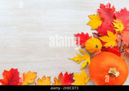 Festliches Herbstdekor aus Kürbissen und Blättern auf Holzhintergrund. Flach Lay Herbst Komposition mit Kopierraum. Stockfoto