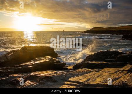 Constantine Bay, Cornwall, England, Großbritannien, wenn die goldene Sonne im Spätsommer über dem Atlantik untergeht. Die Felsen und das Meer reflektieren das goldene Licht Stockfoto