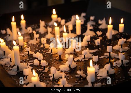 Kerzen auf einem großen Kerzenständer mit vielen ausgebrannten Kerzen und einigen brennenden Kerzen in einer Kirche Stockfoto