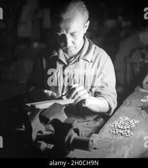 In einer Fabrik zur Herstellung der Kriegsauszeichnung 'Eisernes Kreuz', hier: feilen und politischen, Deutschland 1930er Jahre. In einer Fabrik, die das "Eiserne Kreuz", eine deutsche Kriegsmedaille, hier produziert: Raspeln und Polieren, Deutschland 1930er Jahre Stockfoto