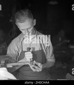 In einer Fabrik zur Herstellung der Kriegsauszeichnung 'Eisernes Kreuz', hier: polieren, Deutschland 1930er Jahre. In einer Fabrik, die das "Eiserne Kreuz", eine deutsche Kriegsmedaille, hier produziert: Polieren, Deutschland 1930er Jahre Stockfoto