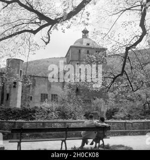 Ein Paar sitzt auf einer Bank vor dem Schloss in Heidelberg, Deutschland 1930er Jahre. Ein paar sitzt auf einer Bank vor der Heidelberger Schloss, Deutschland 1930. Stockfoto