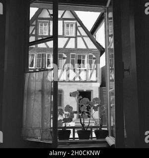 Blick durch ein geöffnetes Fenster in ein Fachwerkhaus, Deutschland 1930er Jahre. Blick durch ein geöffnetes Fenster, um ein Fachwerkhaus, Deutschland 1930. Stockfoto