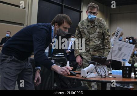 Personal Sgt. Matthew Tybor vom 108. Multifunktionalen medizinischen Bataillon der Illinois Army National Guard diskutiert am 25. Januar ein IT-Problem mit Jacob Budzowski von Cerner Corp., einem Auftragnehmer für Cook County Health, auf dem Massenimpfgebiet COVID-19 des Tinley Park Convention Center in Tinley Park, Illinois. Tybor, der in Tinley Park lebt, sagte, dass die Arbeit am Standort für ihn von großer Bedeutung ist, besonders da er seinen Vater Terrence am 28. November an COVID-19 verloren hat. „Es ist sowohl fantastisch als auch surreal“, sagte er. „Ich bin sehr glücklich, auf dieser Mission zu sein und zu helfen, diesem pa ein Ende zu bereiten Stockfoto