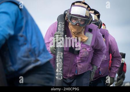 210125-N-QD512-1047 ATLANTIK (JAN 25, 2020) Seeleute bewegen einen Kraftstoffschlauch auf dem Flugdeck an Bord des Lenkflugkörper-Zerstörers USS Mitscher der Arleigh-Burke-Klasse (DDG 57). Mitscher ist derzeit im Atlantischen Ozean und führt Operationen als Teil der Dwight D. Eisenhower Carrier Strike Group durch. Stockfoto