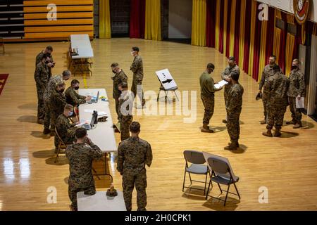 Dienstmitglieder mit 1. Bataillon, 6. Marine-Regiment, 2. Marine-Division beginnen den Screening-Prozess, um den COVID-19-Impfstoff im Göttge Memorial Field House im Marine Corps Base Camp Lejeune, North Carolina, zu erhalten, 25. Januar 2021. Um einen maximalen Durchsatz von Mitarbeitern der II Marine Expeditionary Force zu ermöglichen, wurde das Feldhaus von der Basis vorübergehend umkonfiguriert, um als COVID-19-Impfzentrum ausschließlich für sie zu dienen. Stockfoto