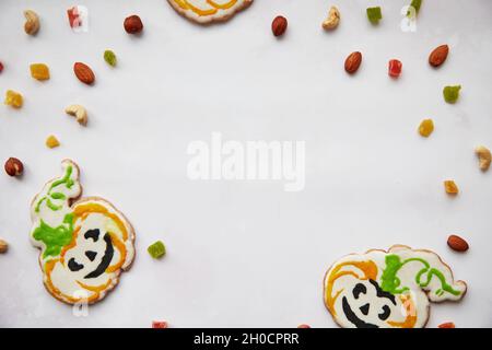 Halloween Kreative Leckereien: Hausgemachte Kürbiskekse mit getrockneten Früchten, kandierte Früchte, Cashewkerne, Haselnüsse. Trick or Treat-Konzept. Herbst gemütliches Haus CO Stockfoto