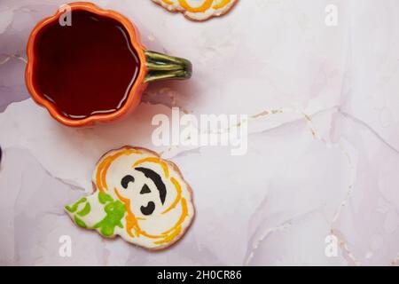 Halloween kreatives Konzept Hintergrund: Kürbisbecher und hausgemachter Keks in Form von niedlichem Kürbis. Ästhetische Herbststimmung oder Trick or Treat Konzept. Autu Stockfoto