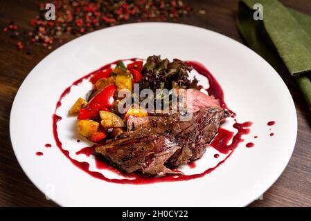 Chateaubriand von zartem Rindfleisch in Bordeaux-Weinsauce mit Gemüsesauce. Großer Teller mit Speisen auf einem dunkelbraunen Holzhintergrund. Stockfoto