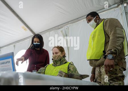Sabrina Khan M.D., eine Ärztin, die mit dem klinischen Datenverwaltungssystem arbeitet und dem Gesundheitsministerium des US-Bundesstaates New York zugewiesen ist, bietet dem NY Naval Miliz Petty Officer 3rd Class Christina Bobrowsky eine Anleitung für die sichere Dateneingabe, Boatswanes Mate 3, der während des Frachtumschlags Ausrüstung betreibt und eine sag-AFTRA-Schauspielerin ist, die dem New York City Navy Operational Support Center und dem U.S. Army PFC zugewiesen wurde. Horace Thompson, ein Besatzungsmitglied des Artillerietanons, der C Bataillon 1 258. Feldartillerie zugewiesen wurde, um die staatlichen Bemühungen zu unterstützen, massenhafte COVID-19-Impfungen admi zu liefern Stockfoto