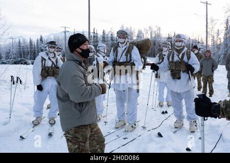 Armee 1. LT. Moses Sun, Vordergrund, ein Zugführer mit Hauptquartier und Hauptquartier, 1. Bataillon, 501. Fallschirmjäger-Infanterie-Regiment, 4. Infanterie-Brigade-Kampfteam (Airborne), 25. Infanterie-Division, U.S. Army Alaska, gibt einen Sicherheitsbrief während der Vorbereitung auf eine Skijoring-Übung auf der Joint Base Elmendorf-Richardson, Alaska, 27. Januar 2021. Das Training evaluierte die Fähigkeiten der arktischen Soldaten mehrerer Teams von Fallschirmjägern von ‘1 Geronimo’, um die beste Gruppe für die kommenden USARAK Arctic Winter Games 2021 auszuwählen. Sun kommt aus Los Angeles, Kalifornien. Stockfoto