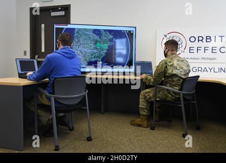 Clyde Stanfield, Vice President of Radar Processes, Orbital Effects und U.S. Army Sgt. Joshua McKee, nicht beauftragter Offizier für die Brandkontrolle, 1. Bataillon, 182. Field Artillery Regiment, Michigan Army National Guard, schaut sich Satellitenbilder an, um während des Northern Strike/„Winter Strike 21“ im Camp Grayling Manöver Training Center, Michigan, am 28. Januar 2021, Ziele zu erreichen. Orbitaleffekte verwendeten Satelliten während der Übung, um die Truppen am Boden bei der Zielerfassung und der Missionsplanung zu unterstützen. Stockfoto