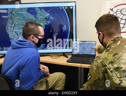 Clyde Stanfield, Vice President of Radar Processes, Orbital Effects und U.S. Army Sgt. Joshua McKee, nicht beauftragter Offizier für die Brandkontrolle, 1. Bataillon, 182. Field Artillery Regiment, Michigan Army National Guard, arbeitet während des Northern Strike/„Winter Strike 21“ im Camp Greyling Manöver Training Center, Michigan, am 28. Januar 2021 im Orbital Effects Office. Orbitaleffekte verwendeten Satelliten während der Übung, um die Truppen am Boden bei der Zielerfassung und der Missionsplanung zu unterstützen. Stockfoto
