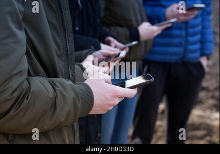 Gruppe von Teenagern mit Handys SMS in der gleichen Zeit Stockfoto