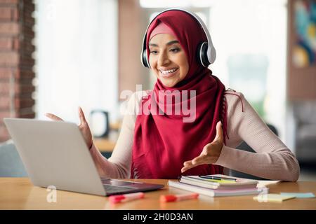 Glückliche muslimische Frau bei einer Videokonferenz mit Kollegen Stockfoto