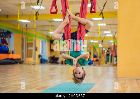 Kleiner Junge, der im Fitnessstudio Yoga in der Luft praktiziert. Lifestyle. Yoga-Konzept für Kinder Stockfoto