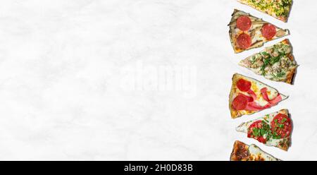 Verschiedene Pizzascheiben auf weißem Marmor aufgereiht. Pizza im Hintergrund Stockfoto