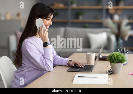 Lächelnde Frau, die am Handy arbeitet und spricht, Seitenansicht des Profils Stockfoto