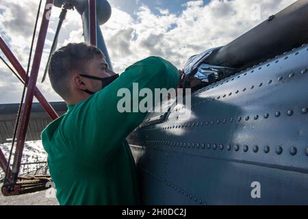 210131-N-RG587-1023 ATLANTIK (JAN 31, 2021) Aviation Electronics Technician Petty Officer 2nd Class Corey Dibiase bereitet einen MH-60R Sea Hawk vor, der an die "Sumpffüchse" des Hubschrauber-Seeschlagergeschwaders 74 angebracht ist, um an Bord des Lenkrakenkreuzers USS Vella Gulf (CG 72) der Ticonderoga-Klasse am 31. Januar 2021 zu reinigen. Vella Gulf führt im Atlantischen Ozean Operationen als Teil der Dwight D. Eisenhower Carrier Strike Group durch. Stockfoto