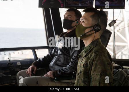 Der erste LT. Kazuhige Mori, ein Pilot-Offizier der 105. Aviation Unit, arbeitet mit dem US Navy LT. Tim McNerney, einem stellvertretenden Luftoffizier des amphibischen Sturmschiffs USS America (LHA 6), während ein JGSDF CH-47 mit 1. Hubschrauber-Brigade, Western Army Aviation Group, Führt an Bord der LHA 6 in der philippinischen See Berührungs- und Go-Übungen durch, 31. Januar 2021. Durch Schulungen mit dem JGSDF verbessert die 31. Marine Expeditionary Unit (MEU) die Interoperabilität und die Fähigkeit, sich mit einem wichtigen Verbündeten zu integrieren. Die 31. MEU ist an Bord von Schiffen der America Expeditionary Str Stockfoto