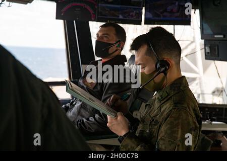 Der erste LT. Kazuhige Mori, ein Pilot-Offizier der 105. Aviation Unit, arbeitet mit dem US Navy LT. Tim McNerney, einem stellvertretenden Luftoffizier des amphibischen Sturmschiffs USS America (LHA 6), während ein JGSDF CH-47 mit 1. Hubschrauber-Brigade, Western Army Aviation Group, Führt an Bord der LHA 6 in der philippinischen See Berührungs- und Go-Übungen durch, 31. Januar 2021. Durch Schulungen mit dem JGSDF verbessert die 31. Marine Expeditionary Unit (MEU) die Interoperabilität und die Fähigkeit, sich mit einem wichtigen Verbündeten zu integrieren. Die 31. MEU ist an Bord von Schiffen der America Expeditionary Str Stockfoto