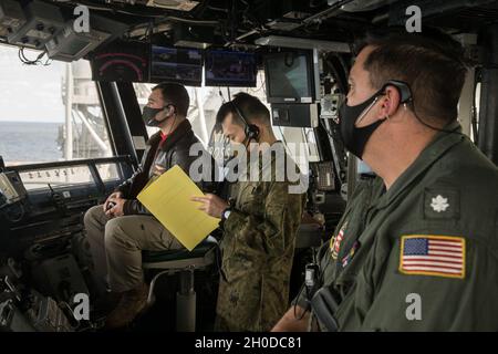 Der erste LT. Kazuhige Mori, ein Pilot-Offizier der 105. Luftfahrteinheit, arbeitet mit dem LT. Tim McNerney der US-Marine, links, einem Assistant Air Officer, und Cmdr. Cliff J. Uddenburg, beide mit amphibischem Angriffsschiff USS America (LHA 6), während eine JGSDF CH-47 mit 1. Hubschrauber-Brigade, Western Army Aviation Group, an Bord der LHA 6 in der philippinischen See Berührungs- und Go-Übungen durchführt, 31. Januar 2021. Durch Schulungen mit dem JGSDF verbessert die 31. Marine Expeditionary Unit (MEU) die Interoperabilität und die Fähigkeit, sich mit einem wichtigen Verbündeten zu integrieren. Der 31. MEU ist im Einsatz mit aboa Stockfoto