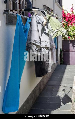 Vertikale Aufnahme von Kleidung, die im Freien trocknet und vom Fenster hängt. Stockfoto