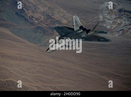 Ein F-22 Raptor, der dem 525. Jagdgeschwader auf der Joint Base Elmendorf-Richardson, Alaska, zugewiesen wurde, fliegt am 1. Februar 2021 über die Nevada Test and Training Range, Nevada. Eine Kombination aus Sensorik, integrierter Avionik, Situationsbewusstsein und Waffen verschafft F-22-Piloten einen First-Look, First-Shot, First-Kill-Vorteil gegenüber Gegnern. Stockfoto