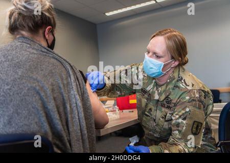 US Army Staff Sgt. Jennifer Garrett mit der Nationalgarde der Michigan Army verwendet einen Alkoholtupfer, um die Injektionsstelle zu reinigen, bevor sie einer Frontarbeiterin des Michigan State Police Headquarters, Lansing, Michigan, am 1. Februar 2021 eine Spritze mit dem Impfstoff Moderna COVID-19 verabreichte. Die Impfteams der Michigan National Guard COVID-19 erweitern sich, wie gefordert, mit lokalen Gesundheitsorganisationen, um die Impfung an Michiganders zu liefern und zu verabreichen. Stockfoto