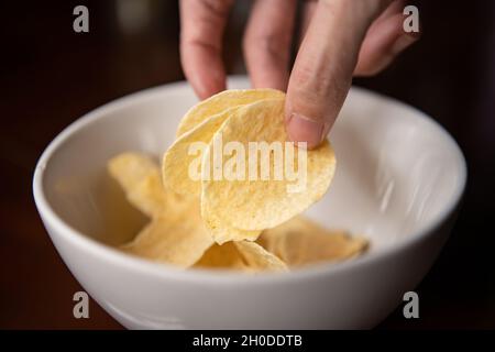 Kartoffelchips aus einer Schüssel pflücken Stockfoto