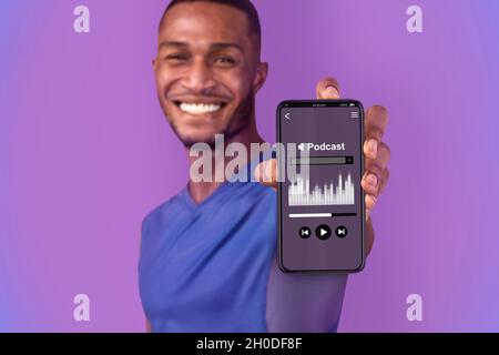 Happy Young Black Man Zeigt Smartphone Mit Musik Podcast Interface Auf Dem Bildschirm Stockfoto